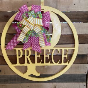 Round yellow, with the initial P and name Preece routed out of the center with a pink, green, and yellow bow attached to the sign.