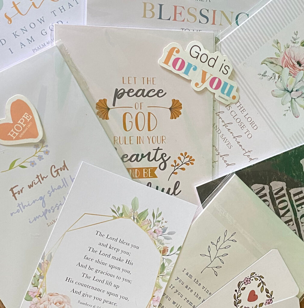 Assortment of white christian note cards with gold and black writing along with multicolored flowers.
