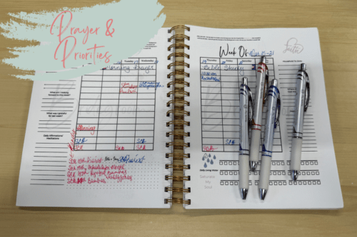 How to Build a Christ-centered morning routine with your planner  with a weekly day by day spread of a planner with vertical sections for each day in black writing and affirmation spots on the edges of each page and habit tracking on the bottom right page and notes on the bottom left. Assorted colors of ink pens are also lying on the spread.